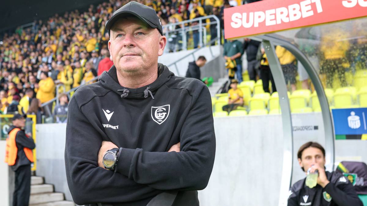 Portret trenera GKS Katowice z ramionami skrzyżowanymi na piersi, stojącego na tle trybun stadionu.