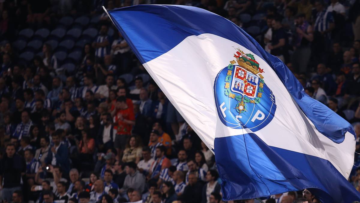 Flaga FC Porto z herbem na tle trybun stadionu wypełnionych kibicami.