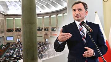 Zbigniew Ziobro przemawia do mikrofonu na tle sali sejmowej.