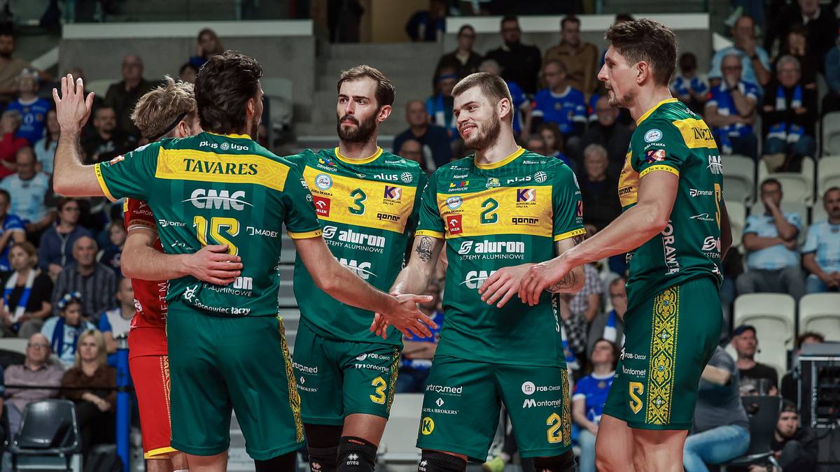 Siatkarze w zielonych strojach świętują na boisku.