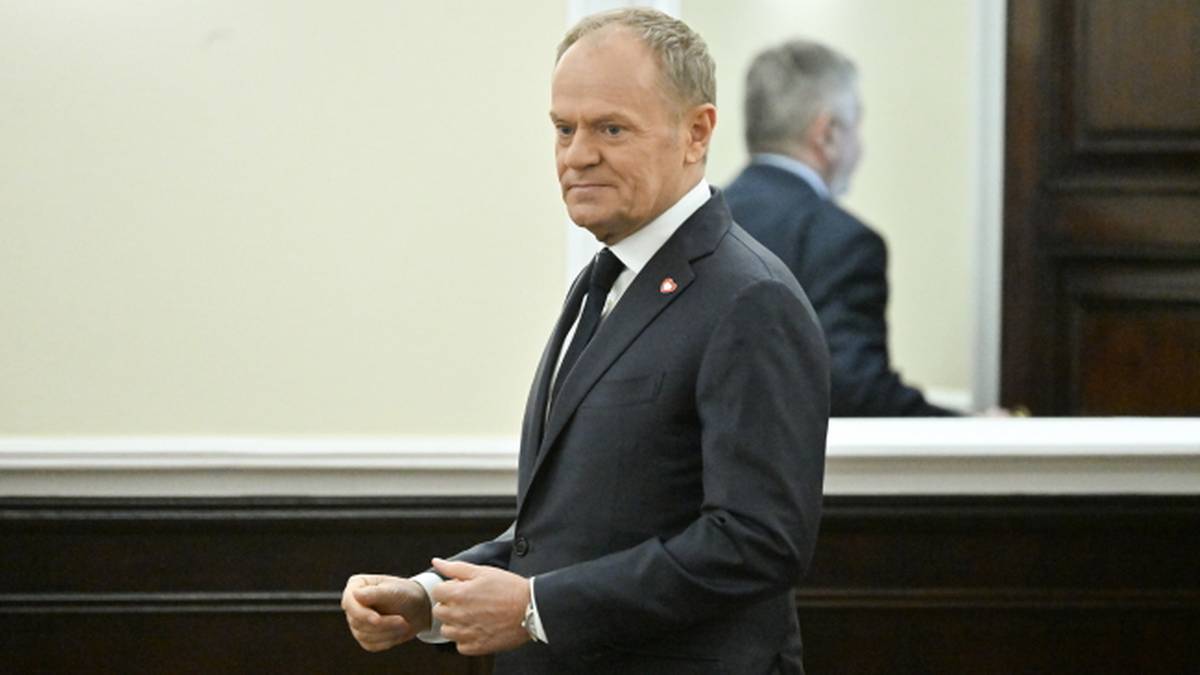 Premier Donald Tusk w garniturze i białej koszuli z czarnym krawatem.