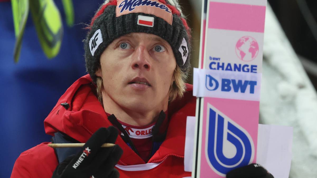 Skoczek narciarski w czapce z polską flagą, przygotowujący się do skoku.