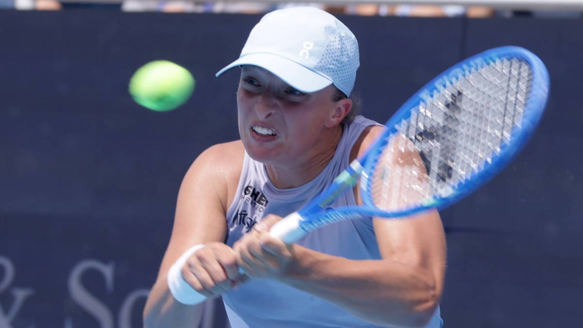 Iga Świątek odbija piłkę rakietą tenisową.