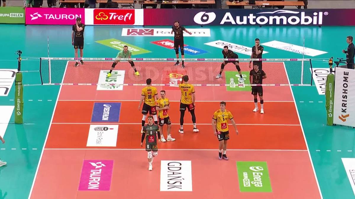Drużyna PGE Projekt Warszawa w żółtych strojach gra w siatkówkę przeciwko drużynie Energa Trefl Gdańsk w czerwonych strojach, akcja meczowa na boisku.