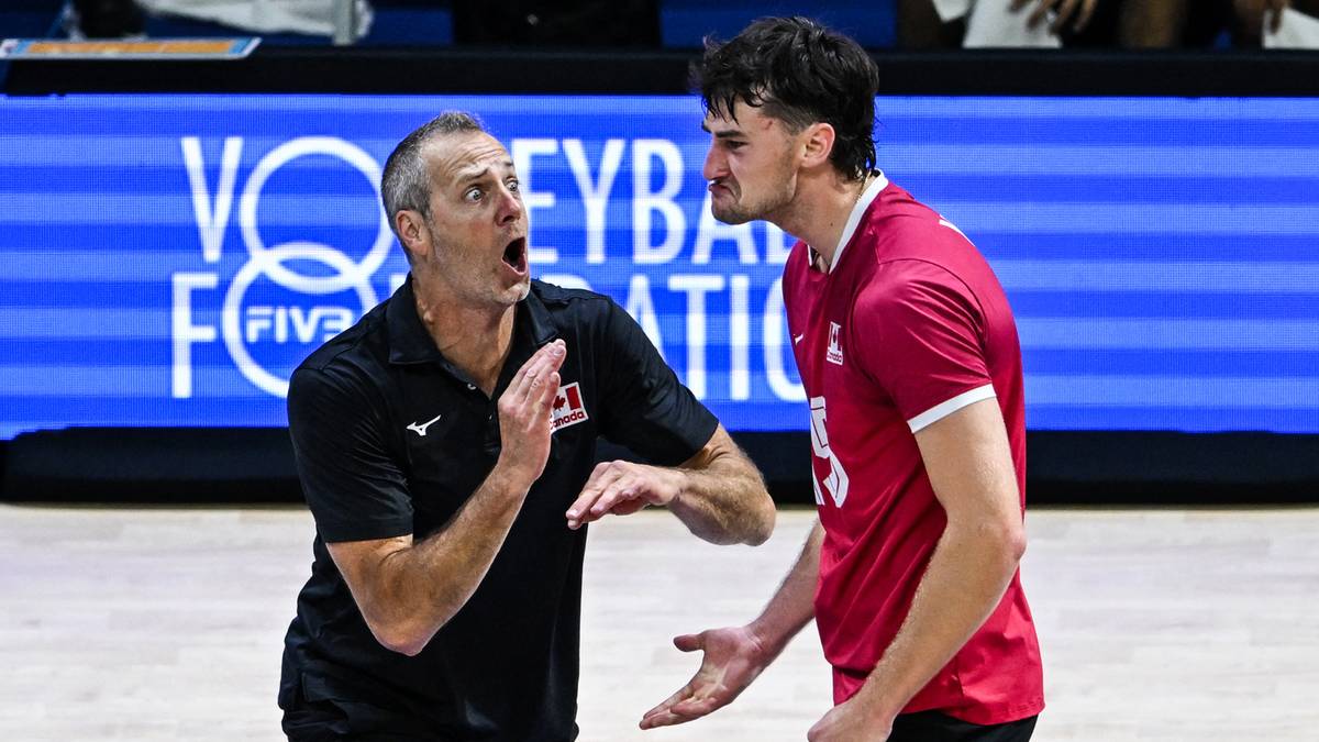 Trener siatkówki w czarnej koszulce z logo Kanady dyskutuje z młodym zawodnikiem w czerwonej koszulce.