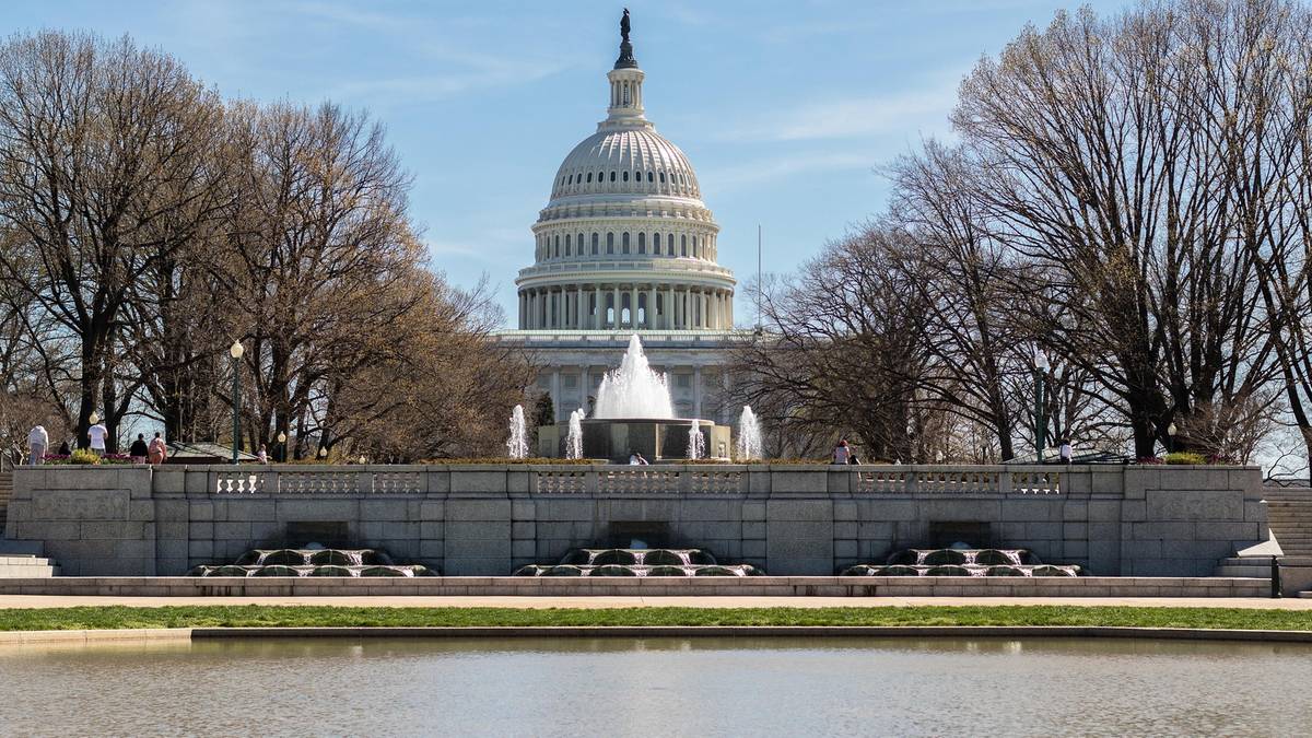 Kapitol Stan&oacute;w Zjednoczonych w Waszyngtonie, siedziba Kongresu USA, z widoczną charakterystyczną kopułą, otoczony drzewami.
