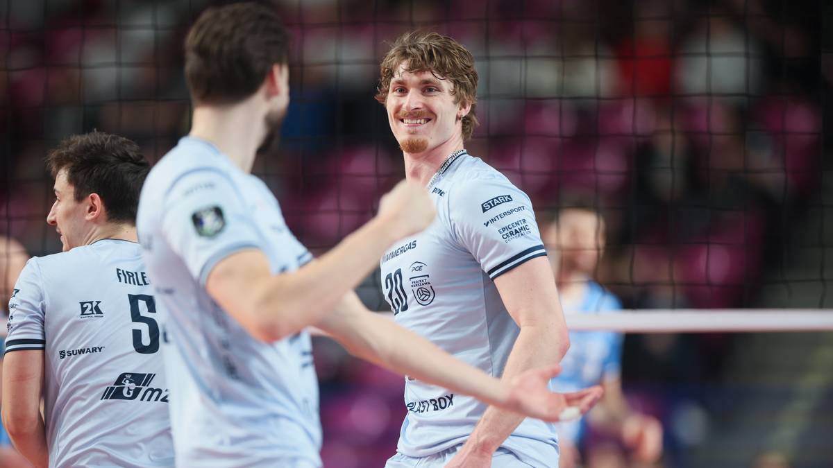 Siatkarze PGE Projekt Warszawa podczas meczu, jeden z nich uśmiecha się do kamery.