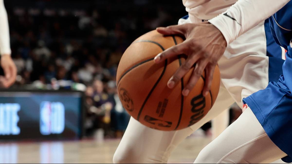 Dwóch koszykarzy walczy o piłkę do koszykówki na boisku.