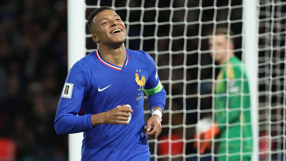 Kylian Mbappe w niebieskiej koszulce reprezentacji Francji cieszy się z gola, za nim bramkarz