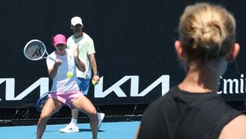 Dwie kobiety grające w tenisa na korcie, jedna z nich uderza piłkę rakietą.