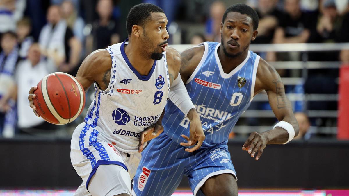 Dwóch koszykarzy w trakcie meczu, jeden prowadzi piłkę, drugi go kryje.