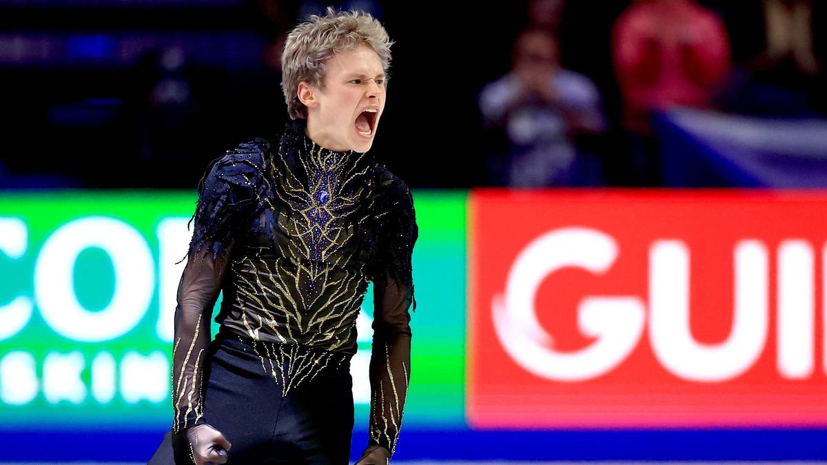 Łyżwiarz figurowy Ilja Malinin z wykrzywioną twarzą i zaciśniętymi pięściami, w trakcie emocjonalnego występu na lodzie podczas zawod&oacute;w.