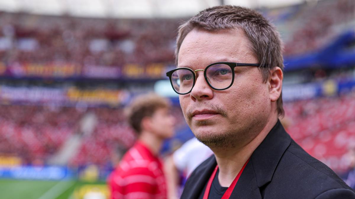 Mężczyzna w okularach na tle stadionu piłkarskiego