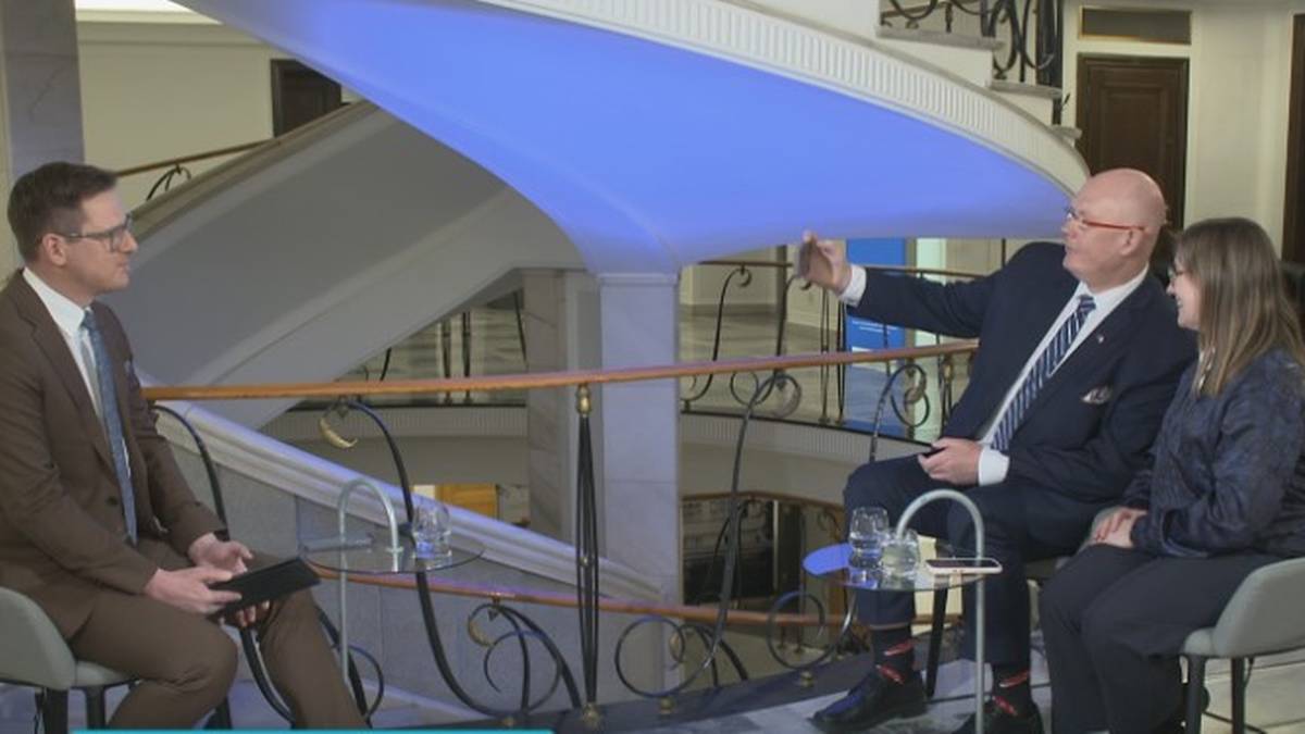 Trzy osoby siedzące, dwie z nich rozmawiają, jedna trzyma telefon.