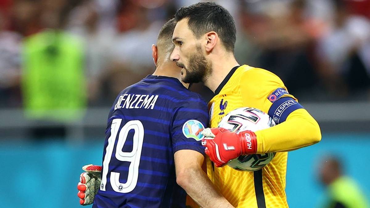 Dw&oacute;ch piłkarzy w strojach sportowych ściska sobie dłonie, jeden z nich trzyma piłkę.