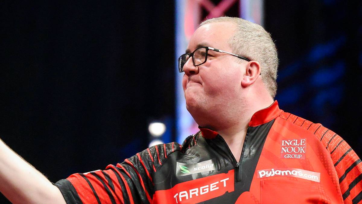 Mężczyzna w okularach rzuca lotką, ubrany w koszulkę z napisem TARGET.