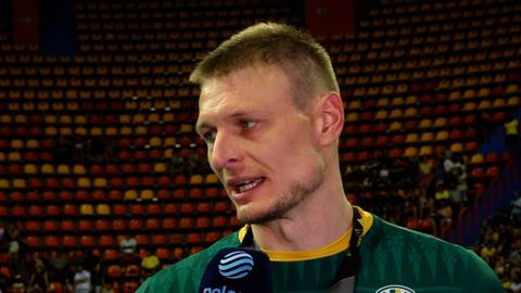 Portret mężczyzny, Jurija Gladry, z bliska, w zielonej koszulce sportowej, z mikrofonem przed ustami.