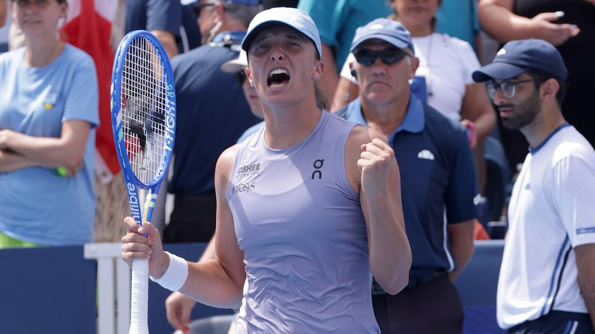 Tenisistka Iga Świątek z uniesioną rakietą i wykrzywionymi ustami podczas meczu, świętując sukces.