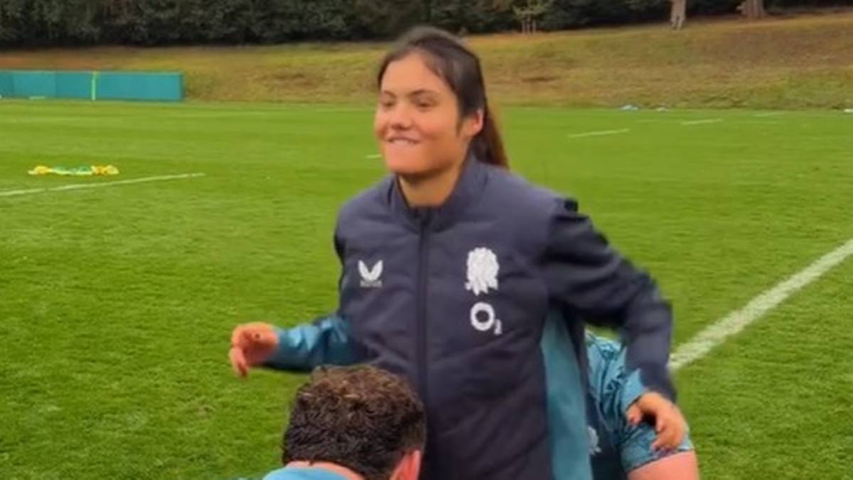 Emma Raducanu na boisku sportowym, uśmiechnięta.