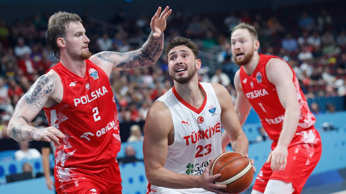 Trzech koszykarzy w akcji podczas meczu. Dwóch w czerwonych strojach z napisem POLSKA, trzeci w białym stroju z napisem TURKIYE.