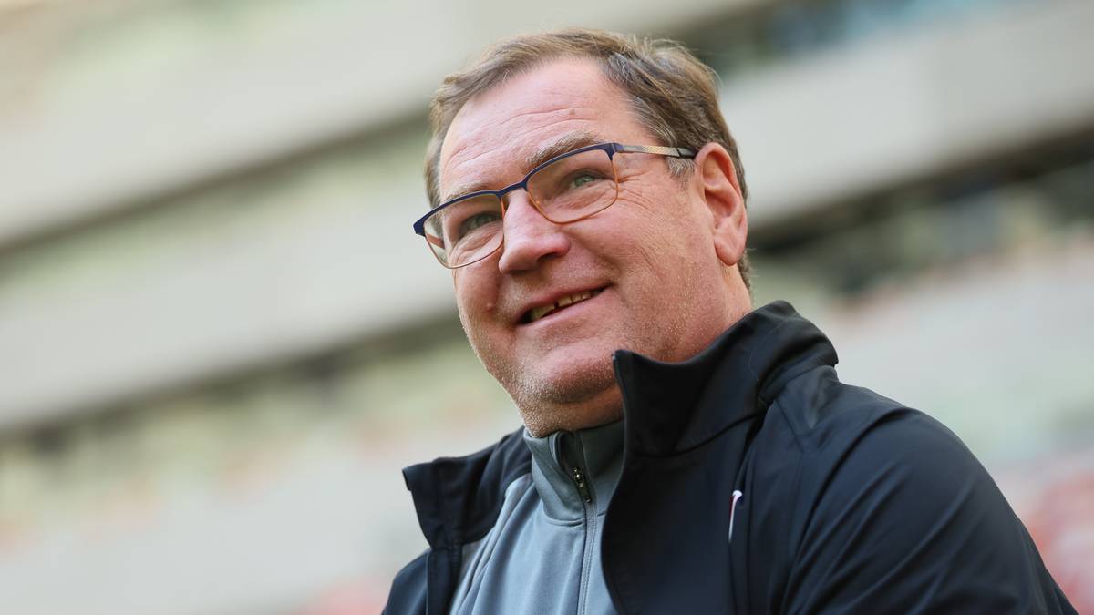 Zbigniew Boniek uśmiecha się, patrząc w bok, ma zaciśnięte dłonie.