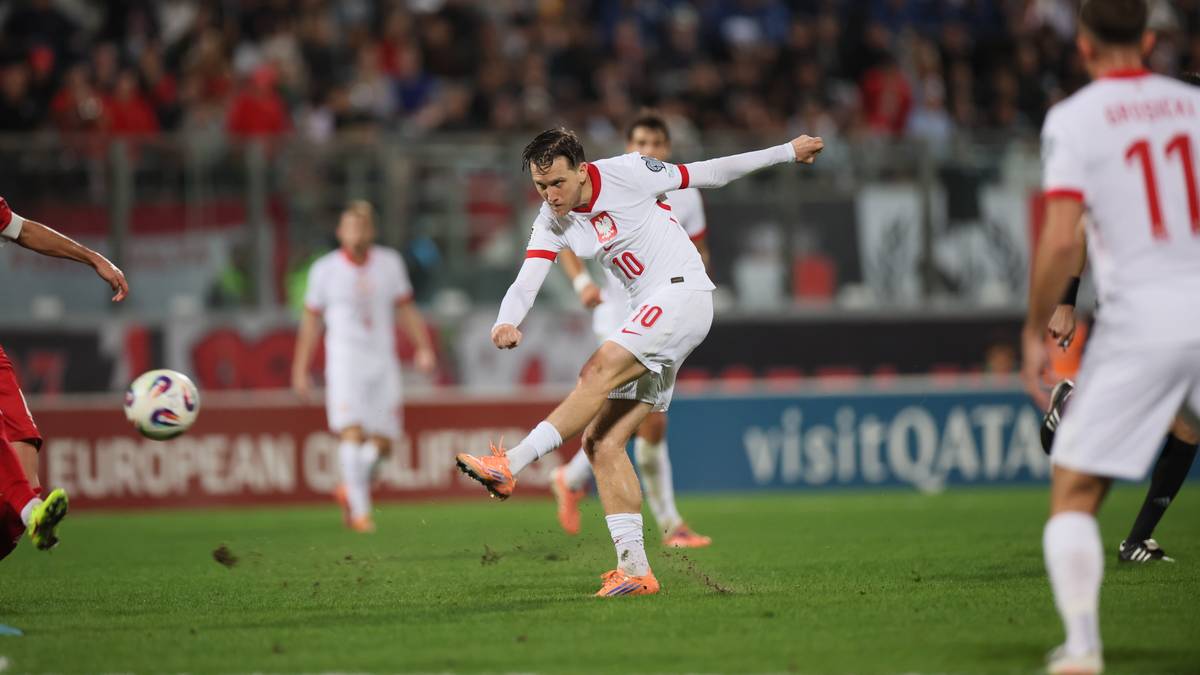 Piłkarz w białej koszulce z numerem 10 na plecach kopie piłkę.