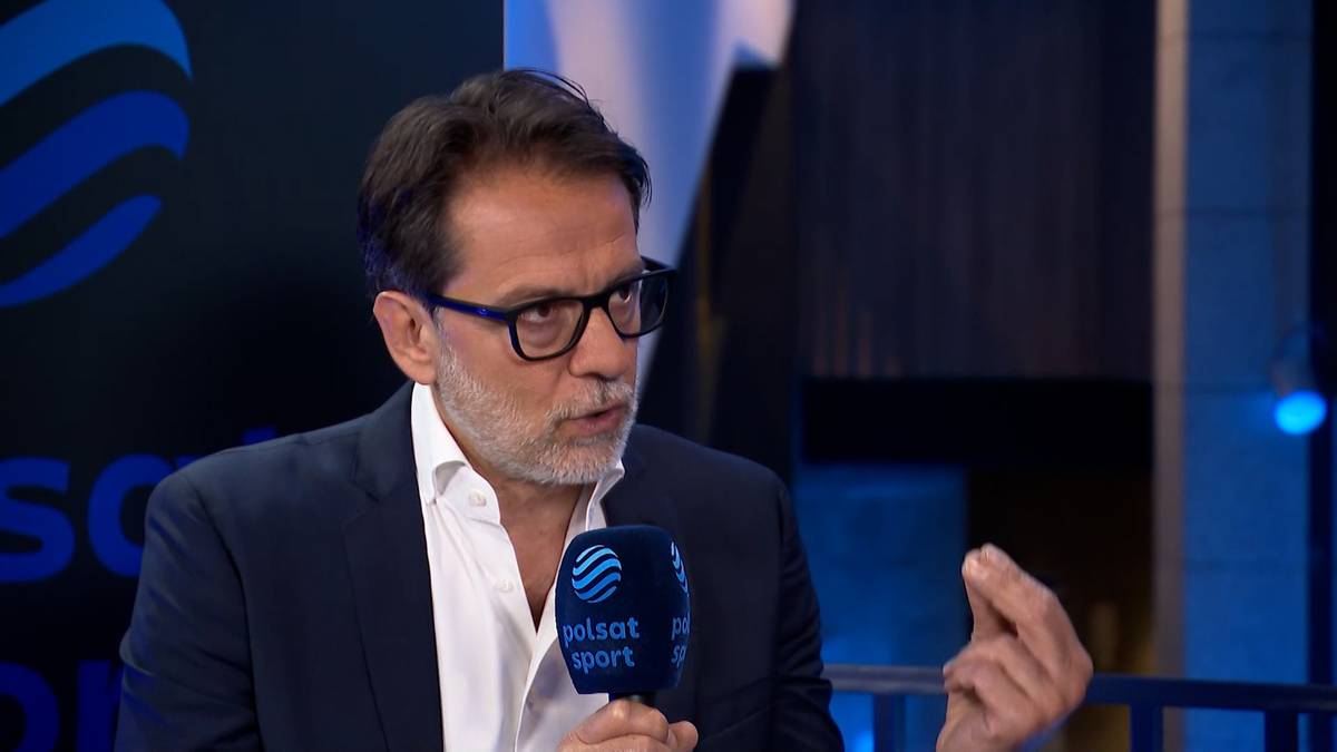 Mężczyzna w okularach i białej koszuli, ubrany w garnitur, mówi do mikrofonu z logo "Polsat Sport". Gestikuluje prawą ręką.