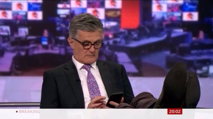 Prezenter BBC z nogami na biurku. Pokazano go na antenie