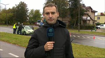 Reporter telewizyjny z mikrofonem na tle miejsca wypadku drogowego w Białymstoku.