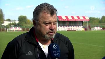 Roman Kosecki podczas wywiadu na tle boiska piłkarskiego.