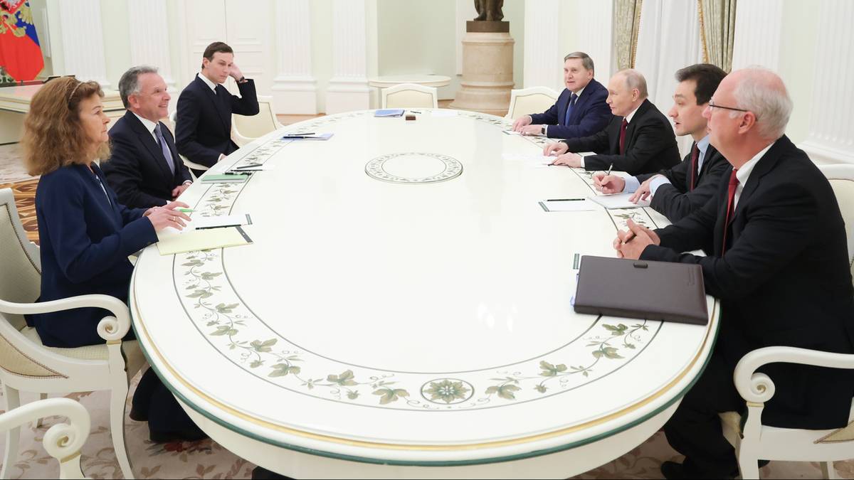 Grupa osób siedzi przy owalnym stole w eleganckim pomieszczeniu, prawdopodobnie podczas spotkania dyplomatycznego.