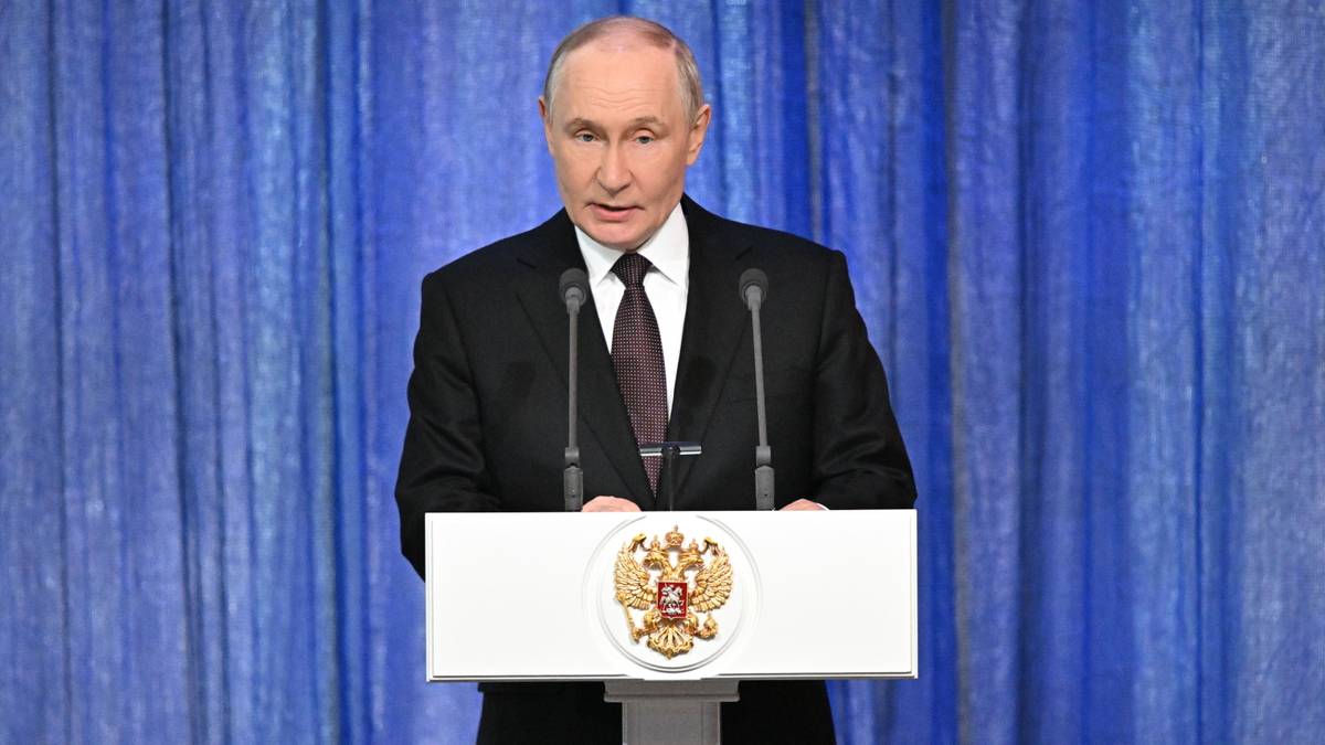 Władimir Putin przemawia za m&oacute;wnicą z herbem Rosji.