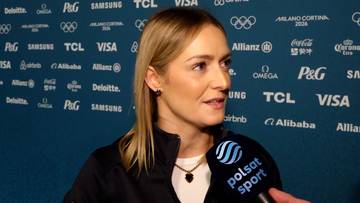 Kobieta z blond włosami, ubrana w ciemną kurtkę i białą koszulkę, udziela wywiadu. W tle widać logo Polsat Sport oraz napisy sponsor&oacute;w igrzysk olimpijskich.