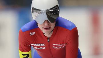 Łyżwiarka w kombinezonie z numerem 3 na rękawie, w kasku i goglach.