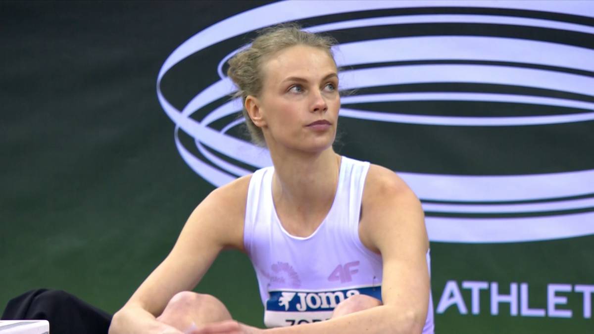 Lekkoatletka Patrycja Żodzik siedzi, skupiona, w białej koszulce sportowej.