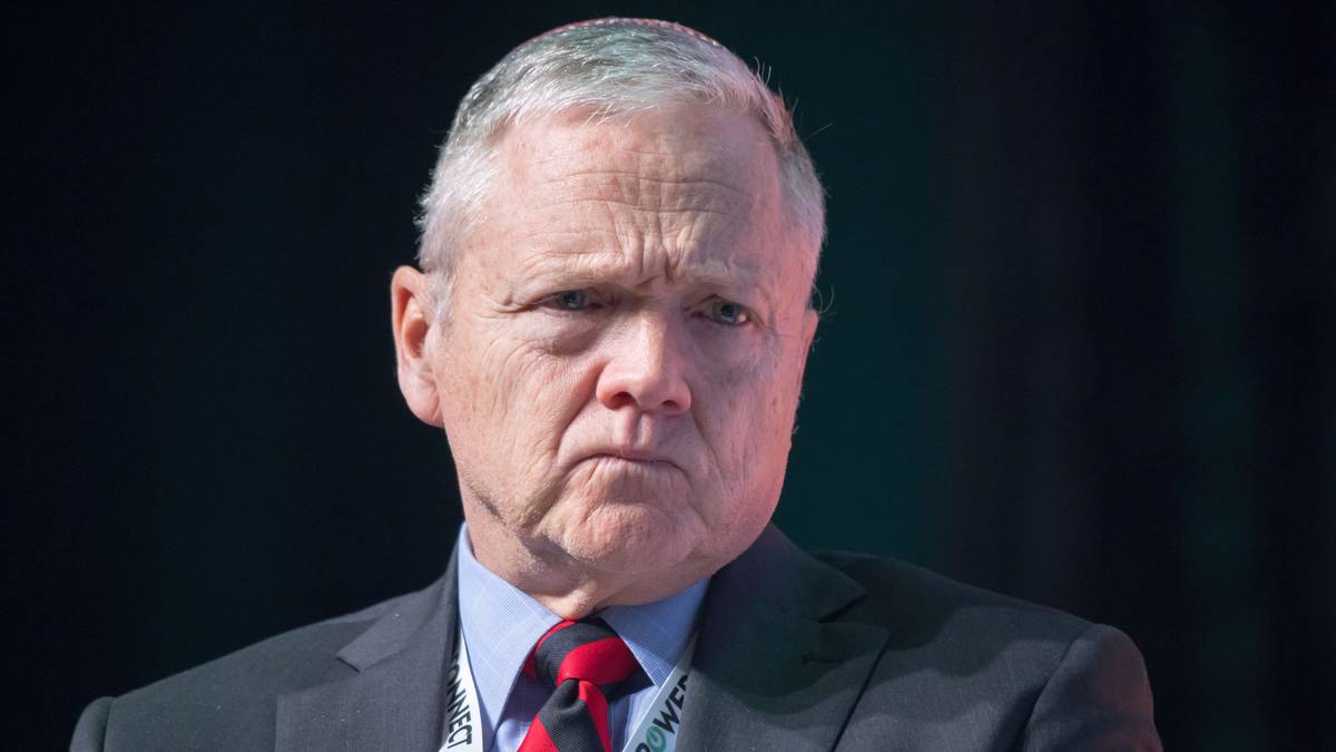 Portret starszego mężczyzny w garniturze, patrzącego wprost z poważną miną.