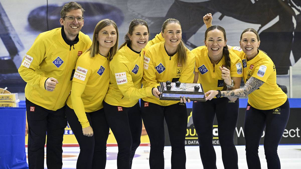 Siedmioosobowa drużyna w żółtych strojach pozuje z uchwytem do curlingu.