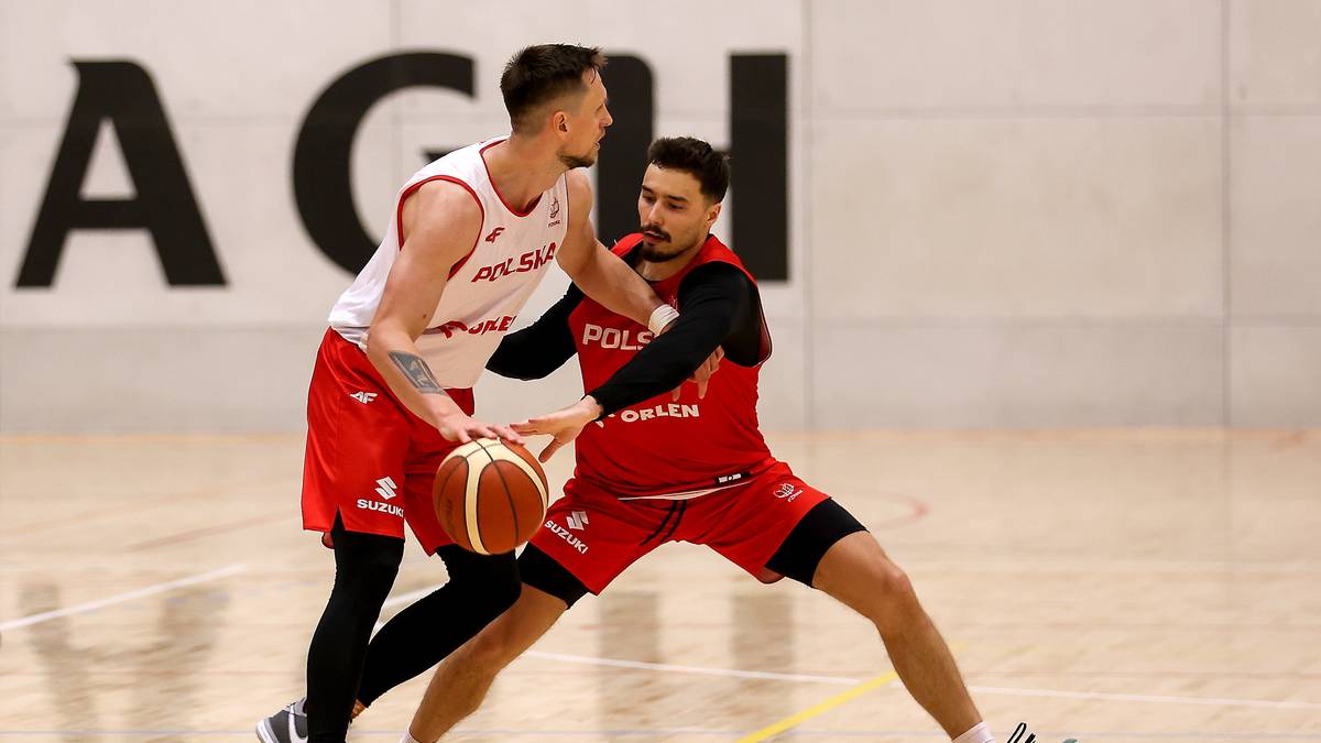 Dwóch koszykarzy w akcji, jeden w białej koszulce z czerwonym napisem "POLSKA", drugi w czerwonej koszulce z tym samym napisem, rywalizuje o piłkę.