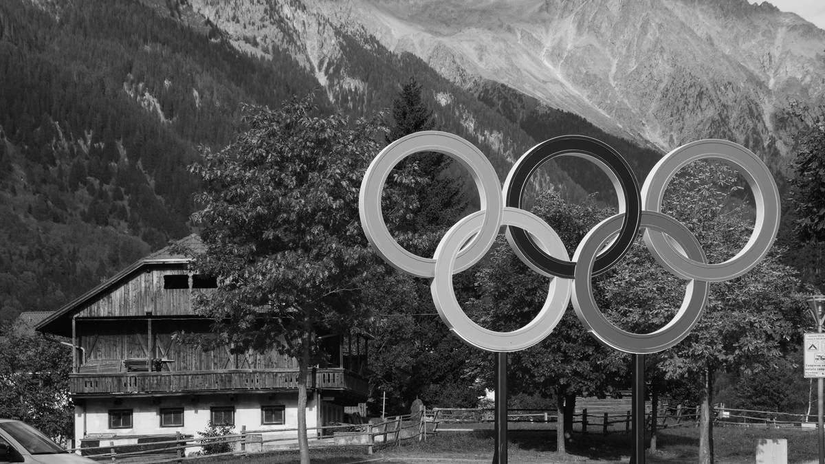 Pięć połączonych kół symbolizujących igrzyska olimpijskie na tle górskiego krajobrazu.