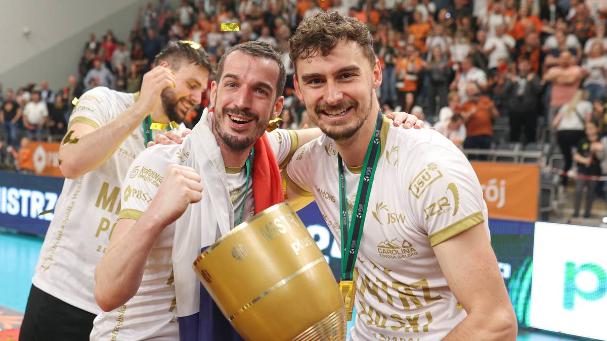 Dw&oacute;ch siatkarzy w złotych medalach i koszulkach drużyny świętuje z pucharem.