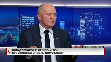 Mężczyzna w garniturze siedzi przed ekranem przedstawiającym nocną panoramę miasta.