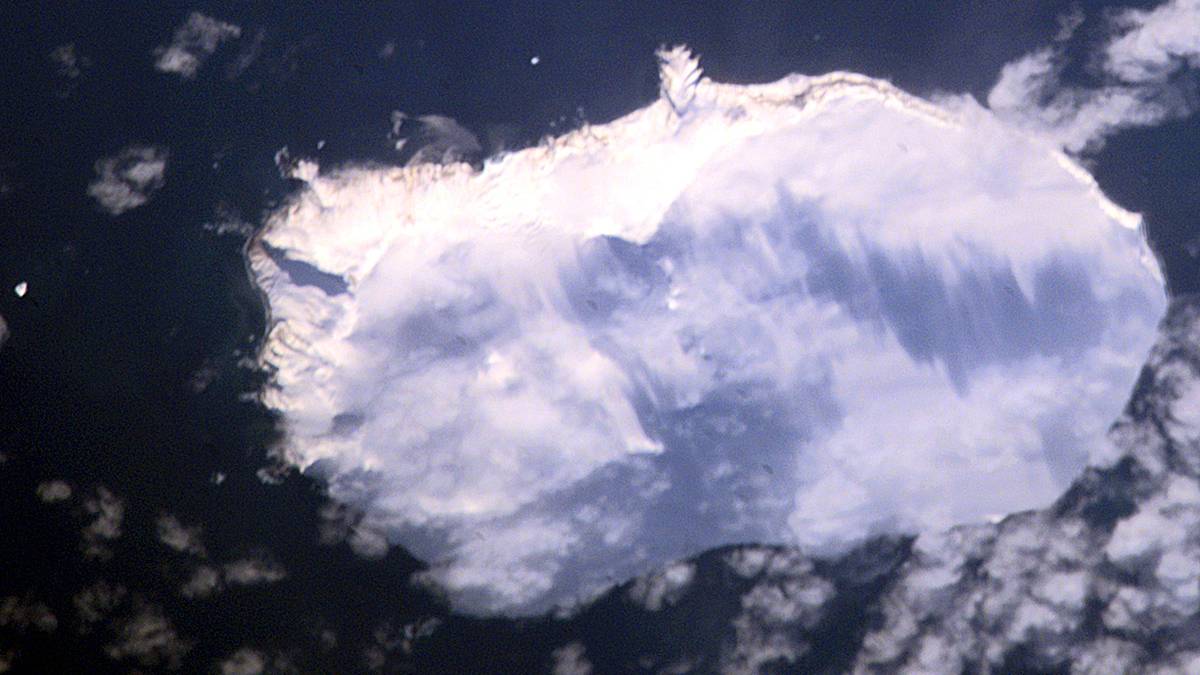 Widok z góry na lodową wyspę otoczoną ciemnym oceanem.