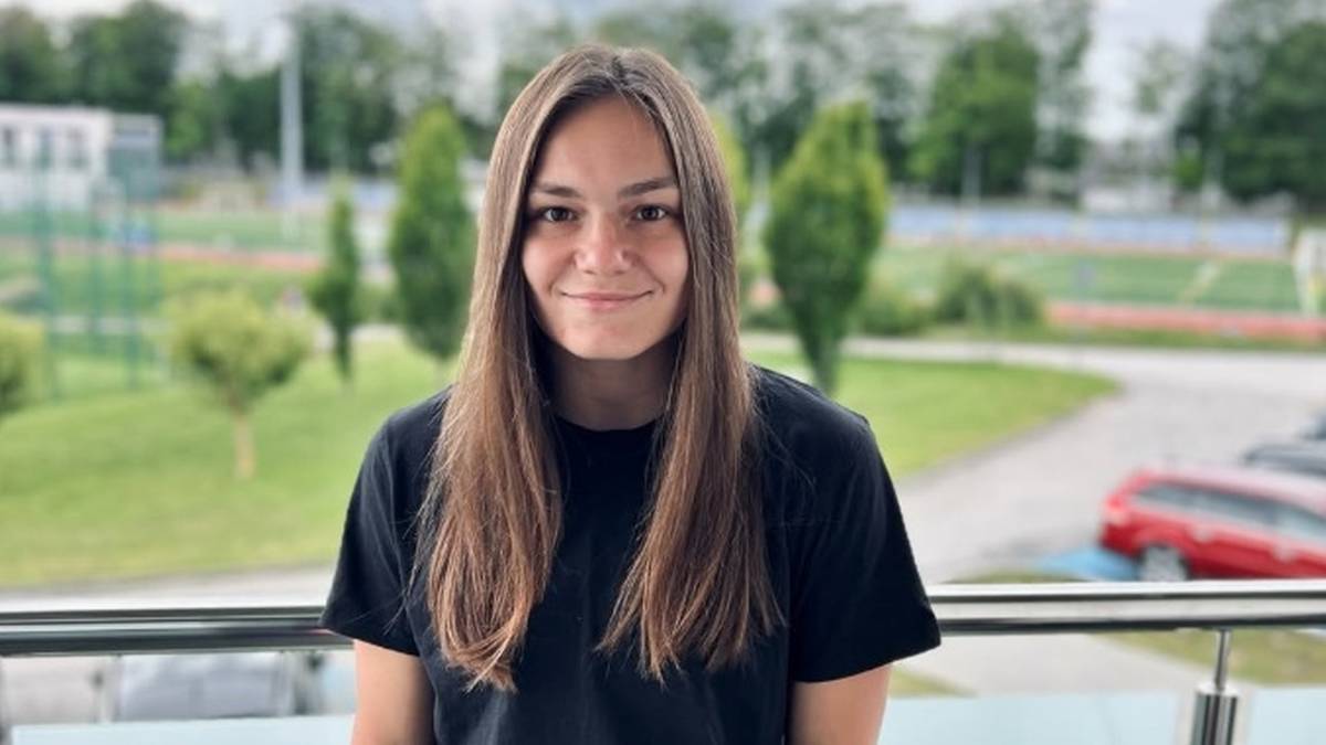 Portret młodej kobiety w czarnej koszulce i dresowych spodniach.