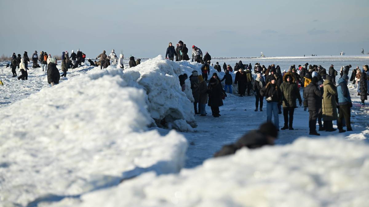 Ludzie obserwują lodowe formacje na zamarzniętym wybrzeżu podczas mroźnego dnia.