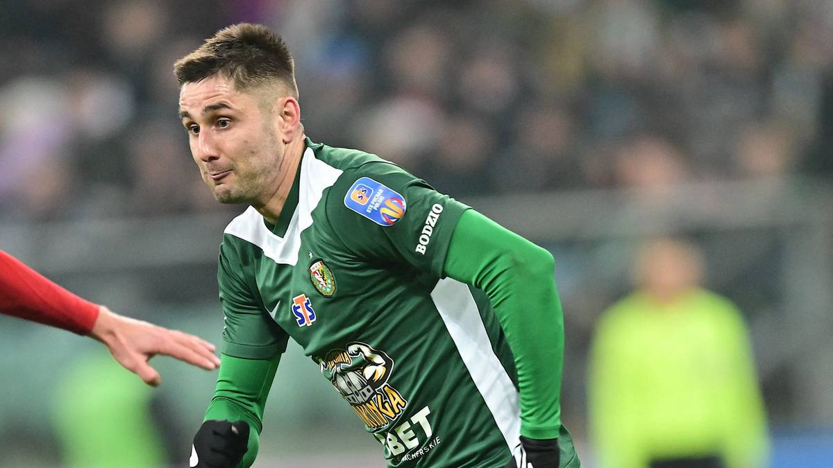 Dwóch piłkarzy rywalizuje o piłkę na boisku.