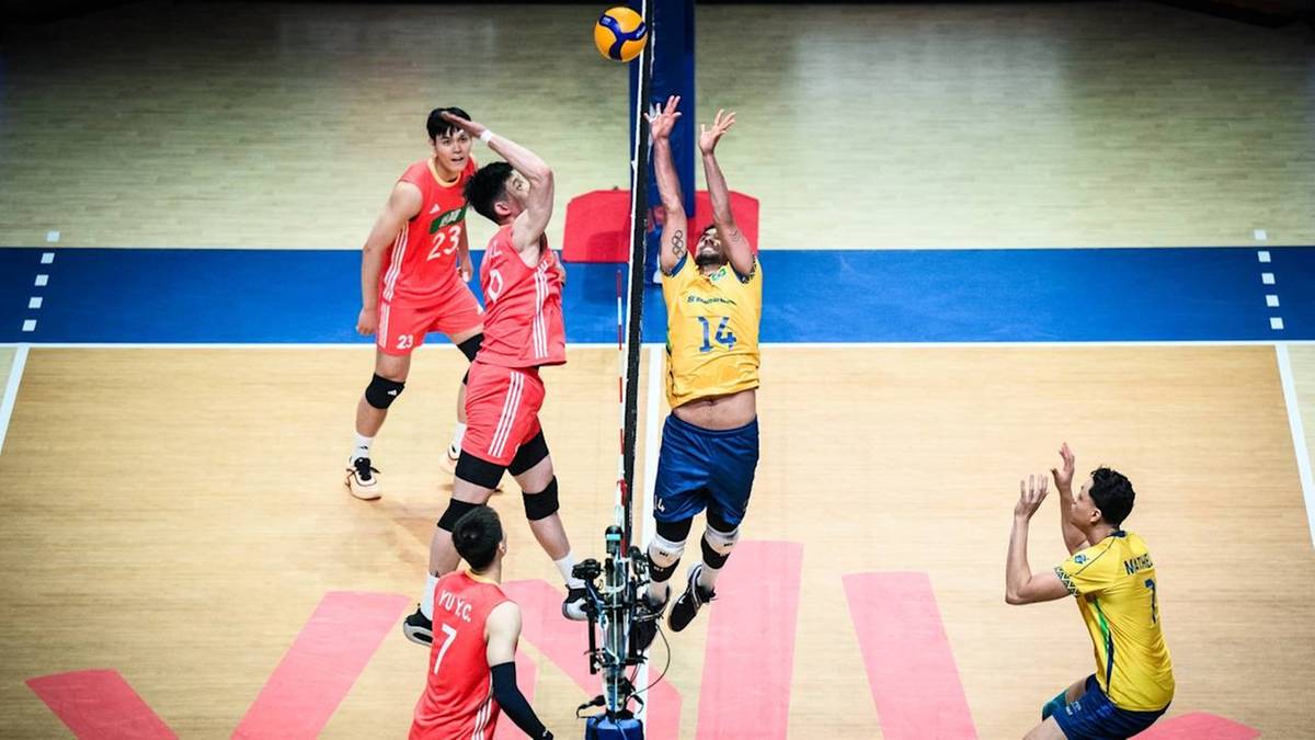 Siatkarze w akcji podczas meczu, jeden z zawodników wykonuje atak nad siatką, drugi próbuje go zablokować.