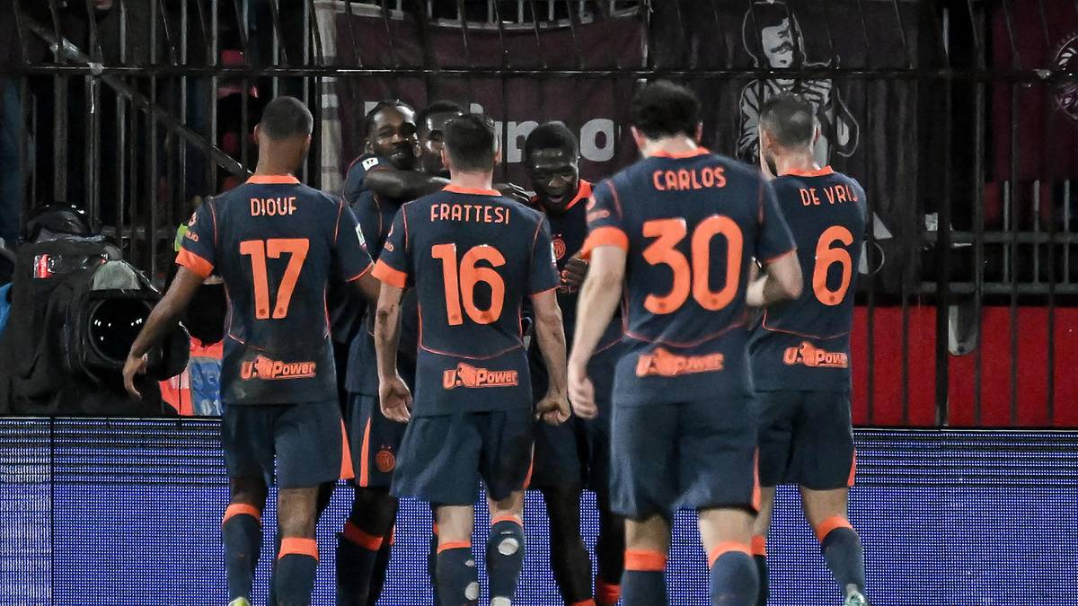 Grupa piłkarzy w pomarańczowo-czarnych strojach świętuje na boisku.