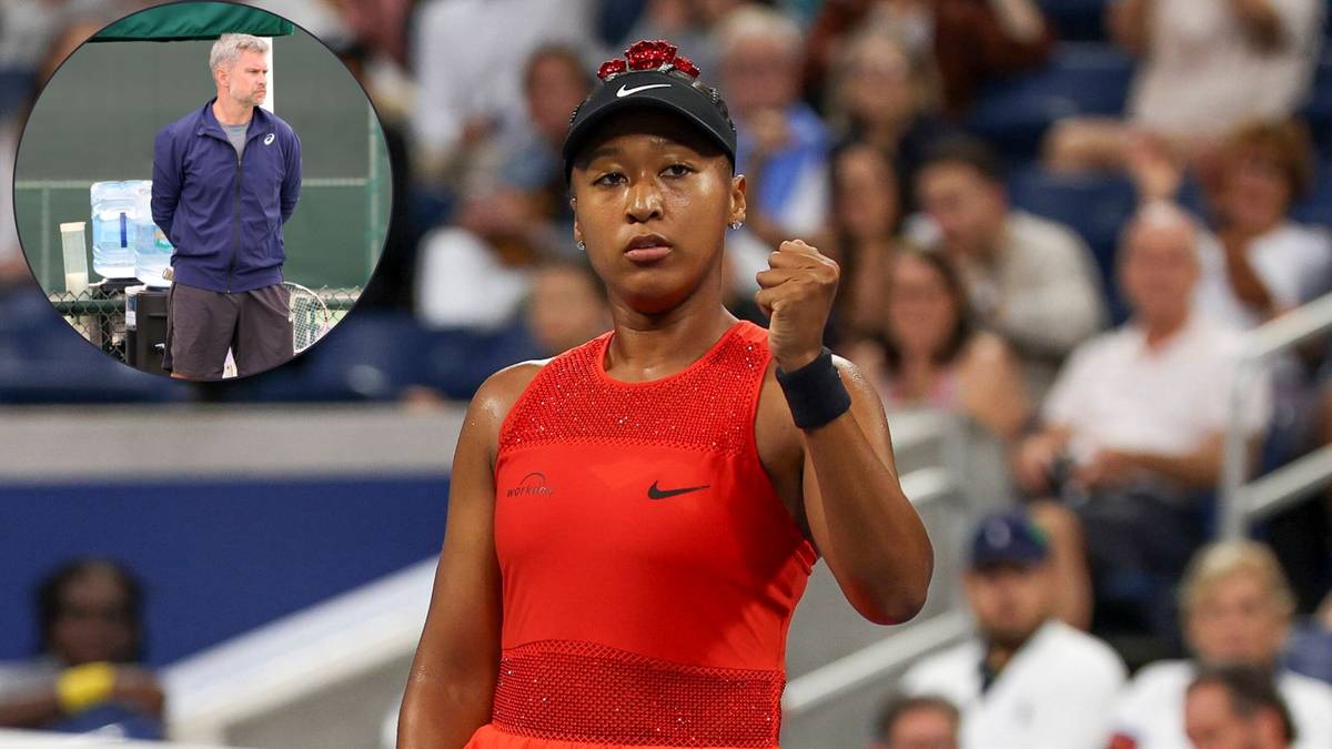 Naomi Osaka, tenisistka, w czerwonej bluzce sportowej z zaciśniętą pięścią, w tle kibice i mały okrągły portret polskiego trenera.
