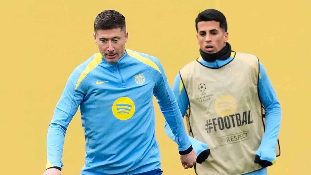 Trzech piłkarzy podczas treningu, dw&oacute;ch stoi, jeden pada na ziemię w trakcie akcji z piłką.