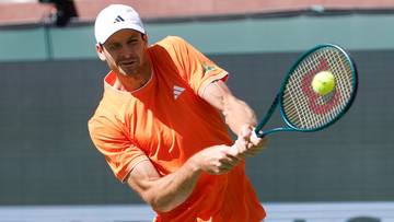 Tenisista Hubert Hurkacz w akcji, odbijający piłkę rakietą podczas meczu.